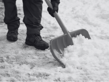 Saisonale Dienstleistungen - Winterdienst Person mit Schaufel, die Schnee von einem Weg räumt.